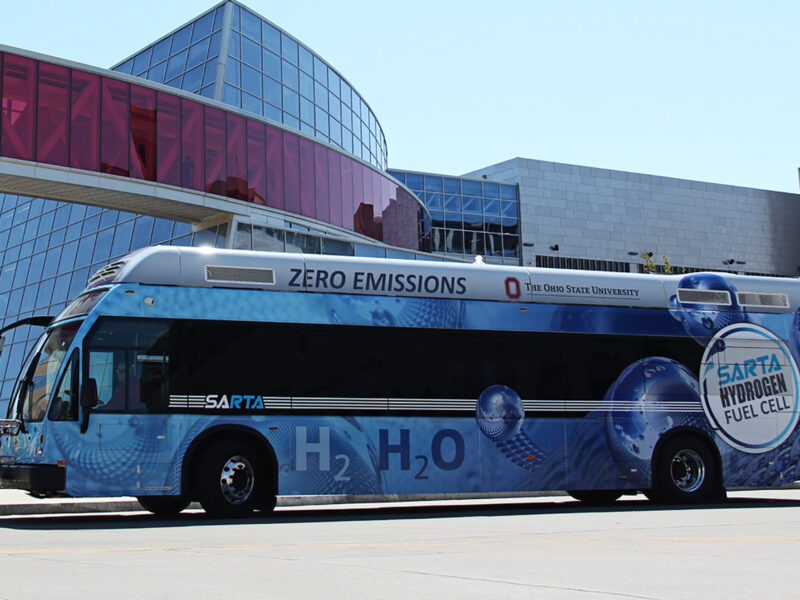 Blue SARTA Hydrogen Fuel Cell bus sitting in front of Building
