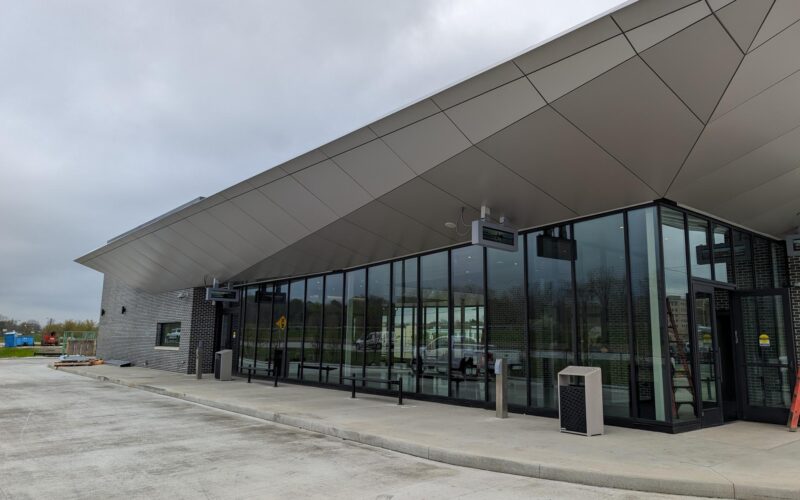 New Massillon Transit Center- A modern transit center with an angular metal roof and large glass windows, creating a sleek and contemporary design. The building is surrounded by a clean concrete area under an overcast sky